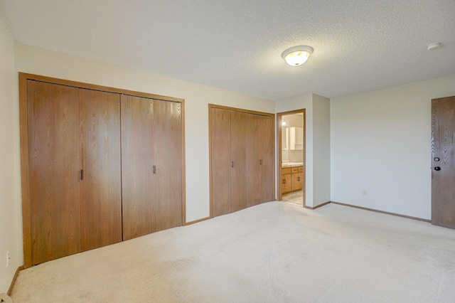14831 Endicott Way Unit 315, Apple Valley, MN 55124 - unfurnished bedroom with two closets, ensuite bathroom, a textured ceiling, light colored carpet, and baseboards