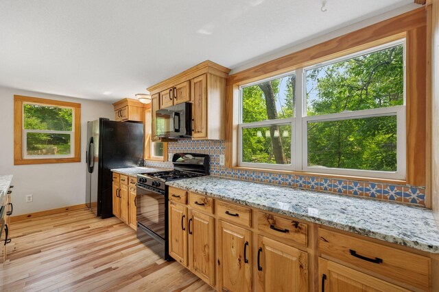 4963 Crofoot Ave NW, Buffalo, MN 55313 - kitchen with black appliances, light wood-style floors, tasteful backsplash, and light stone countertops