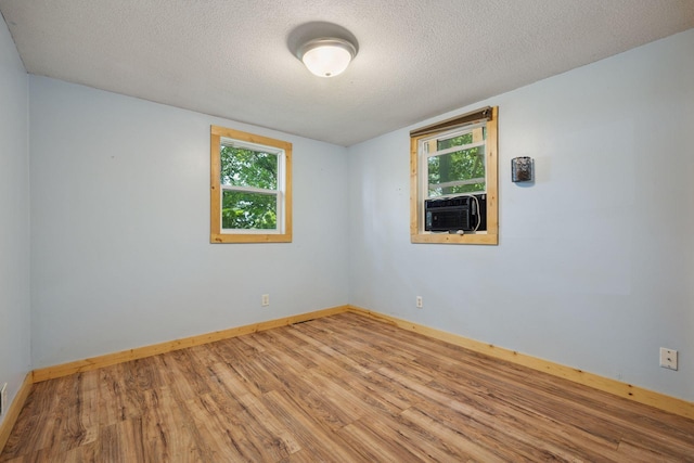 4963 Crofoot Ave NW, Buffalo, MN 55313 - unfurnished room featuring cooling unit, wood finished floors, plenty of natural light, and a textured ceiling