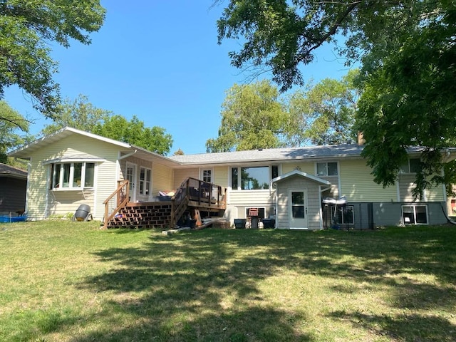 back of property featuring a deck and a lawn