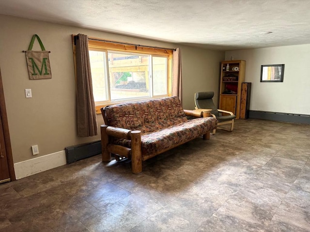 living room featuring a baseboard heating unit, baseboards, and a textured ceiling