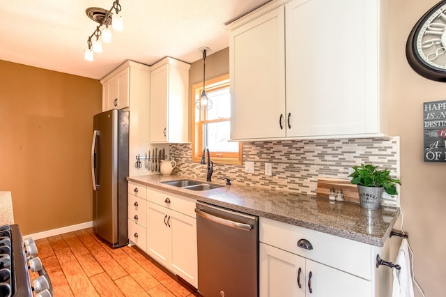 kitchen featuring tasteful backsplash, a sink, white cabinets, light wood-style floors, and stainless steel appliances