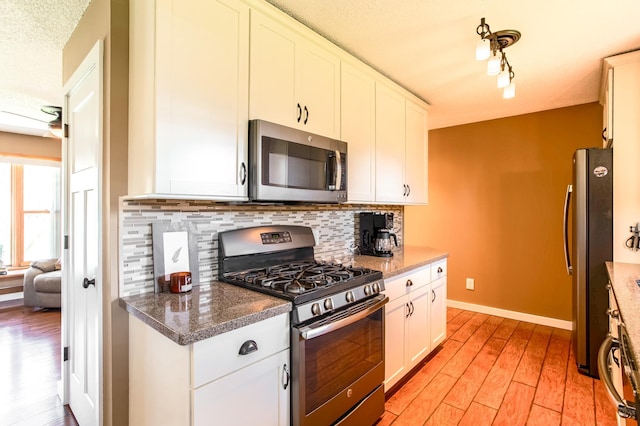 kitchen featuring appliances with stainless steel finishes, decorative backsplash, light wood finished floors, and white cabinets
