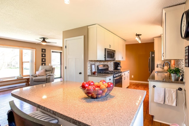 kitchen featuring light wood-style floors, white cabinetry, tasteful backsplash, a sink, and stainless steel appliances