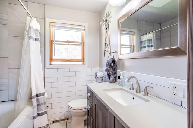 bathroom with toilet, tile walls, plenty of natural light, and vanity