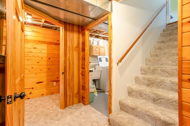 stairs with carpet flooring, wood walls, and washing machine and dryer