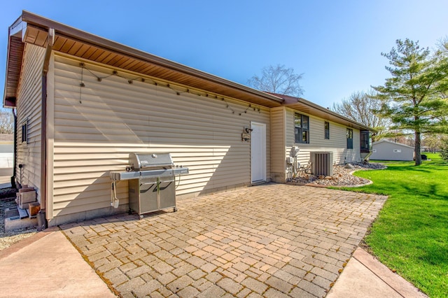 back of house featuring a lawn, cooling unit, and a patio area