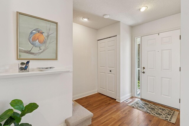 entrance foyer with wood finished floors, baseboards, and a textured ceiling