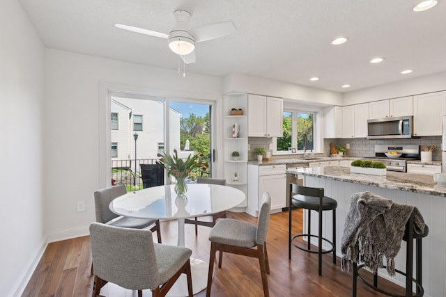 dining space with dark wood-style flooring, baseboards, a ceiling fan, and recessed lighting