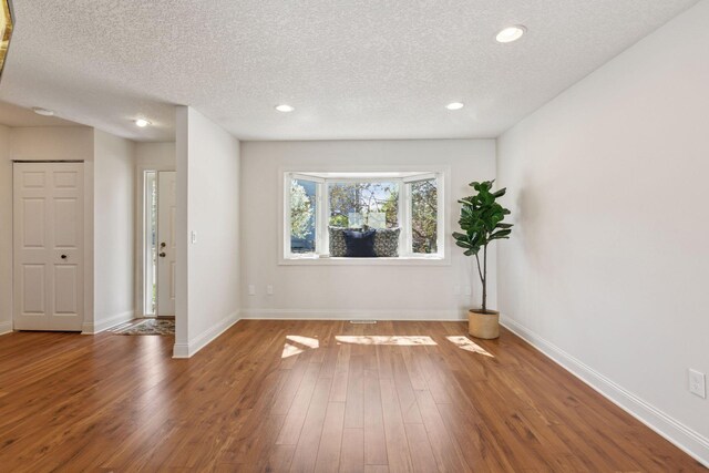 spare room featuring a textured ceiling, wood finished floors, recessed lighting, and baseboards
