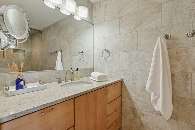 bathroom with tile walls, vanity, and decorative backsplash