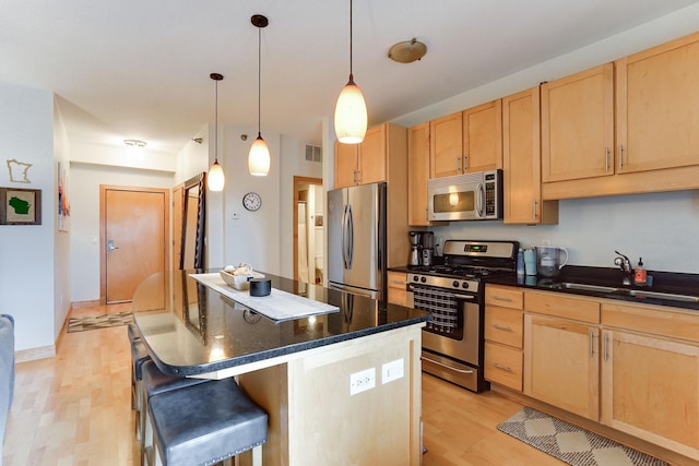 kitchen with stainless steel appliances, light wood-style flooring, a sink, and light brown cabinetry