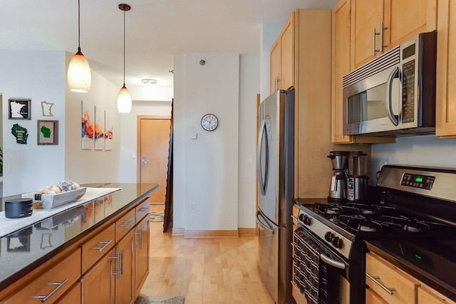 kitchen featuring light wood finished floors, pendant lighting, baseboards, and appliances with stainless steel finishes