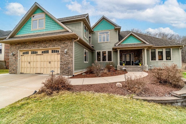 craftsman house with a front yard, concrete driveway, stone siding, and a garage
