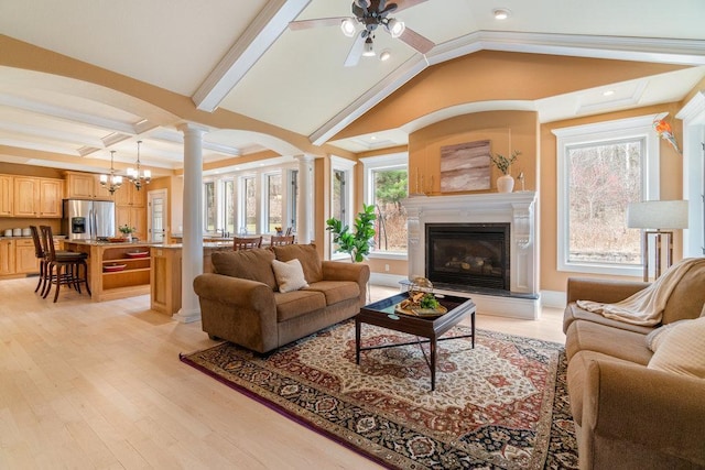 living room with light wood finished floors, ornate columns, a healthy amount of sunlight, and a glass covered fireplace
