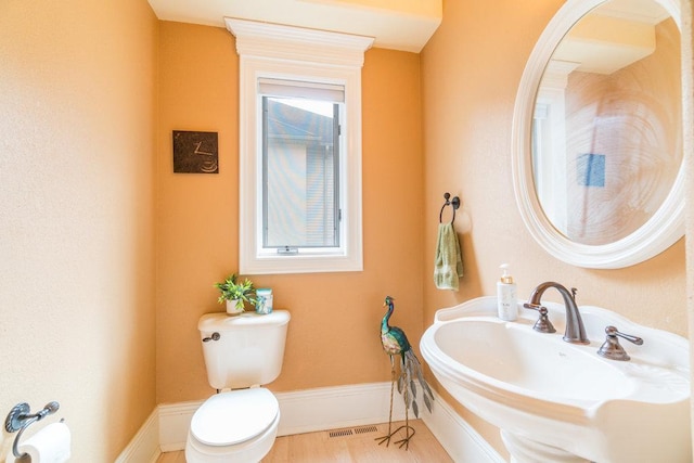 half bathroom featuring visible vents, toilet, and a sink