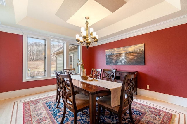 dining room featuring a chandelier, a tray ceiling, baseboards, ornamental molding, and wood finished floors