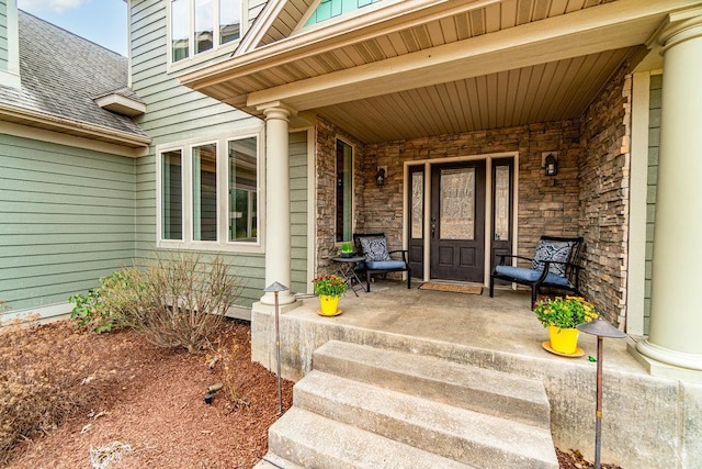 property entrance with a porch, roof with shingles, and stone siding