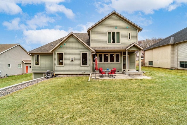 rear view of house featuring a shingled roof, a yard, and a patio area