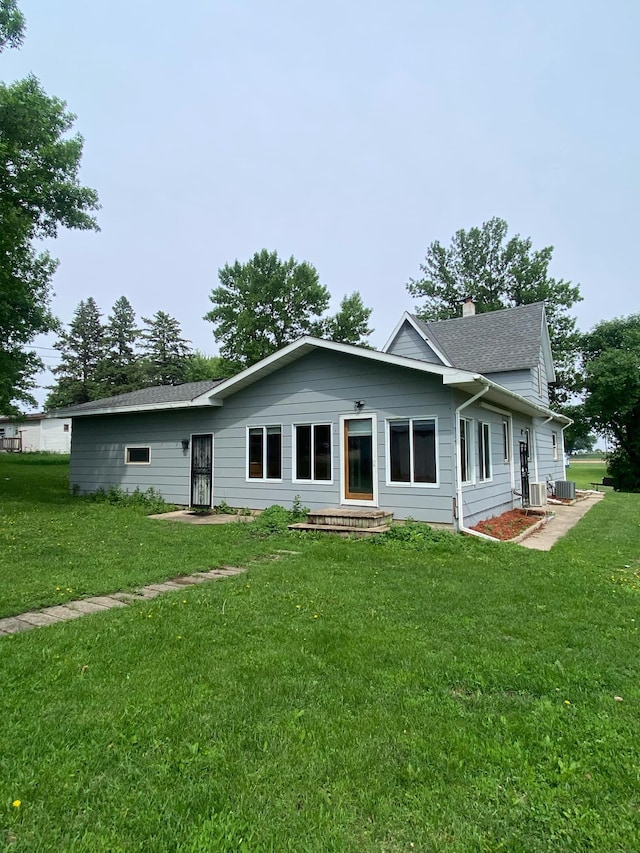 104 3rd St, Buffalo Lake, MN 55314 - back of property featuring cooling unit, a yard, roof with shingles, and a chimney