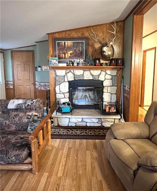 living room featuring a fireplace, wooden walls, wood finished floors, and lofted ceiling