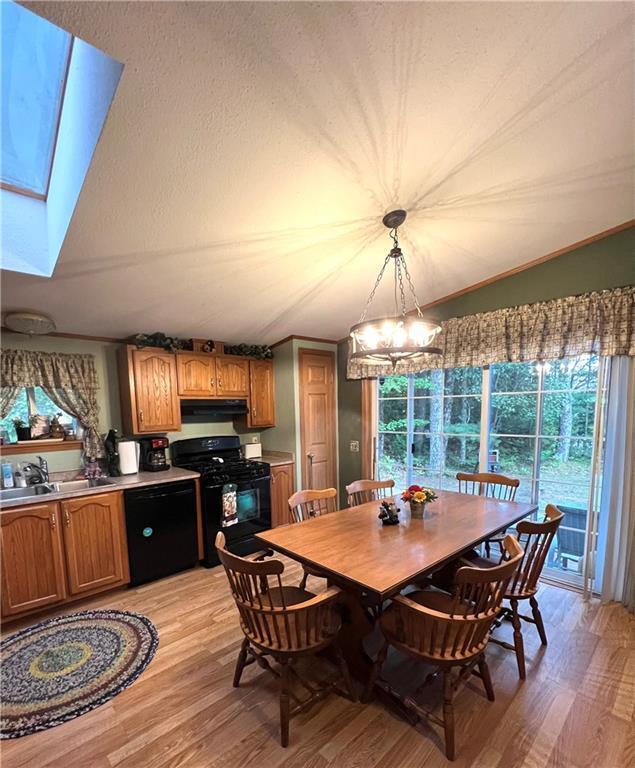 dining space featuring light wood-style floors, a skylight, and an inviting chandelier