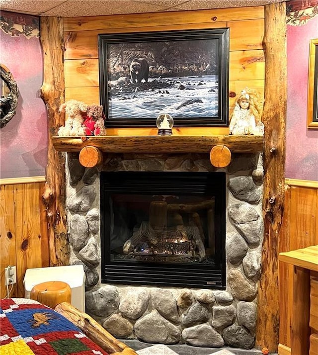 interior details with wainscoting, wood walls, and a fireplace