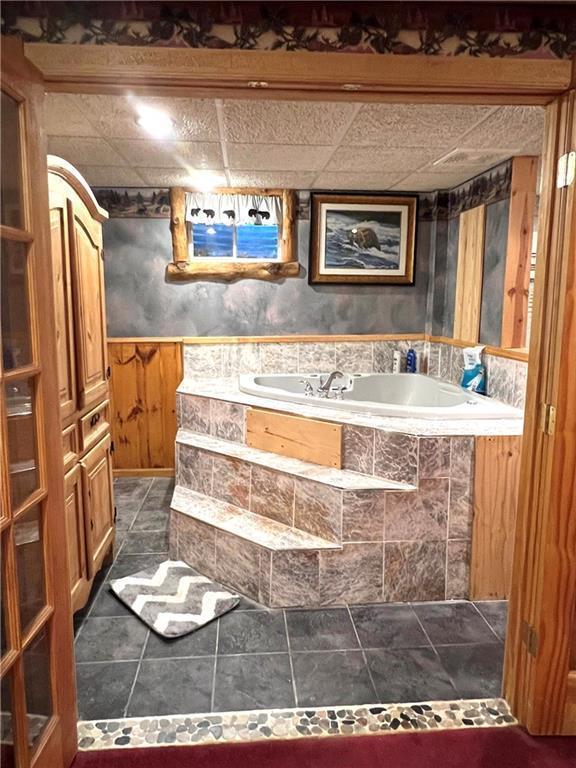 full bathroom with wainscoting, a garden tub, and tile patterned floors