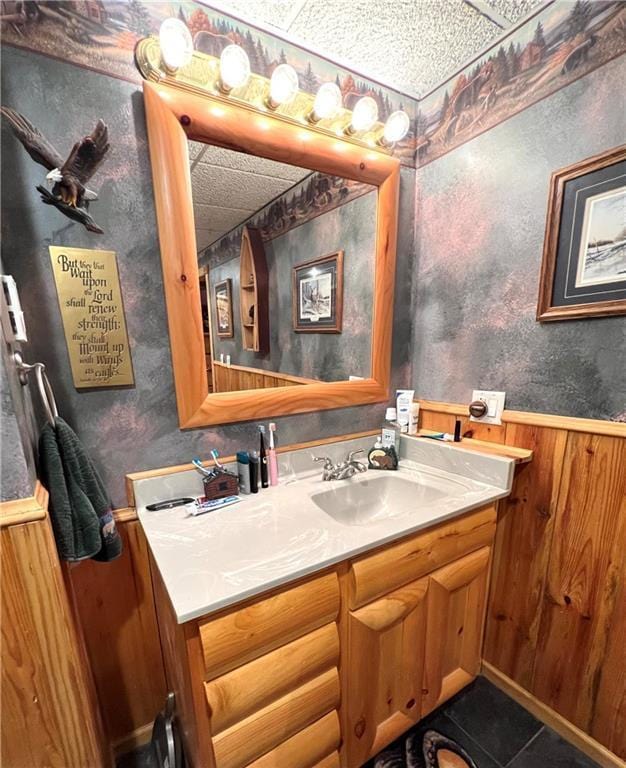 bathroom with tile patterned flooring, vanity, wood walls, and wainscoting