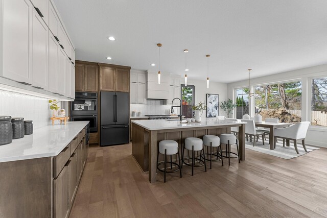 5012 Hankerson Ave, Edina, MN 55436 - kitchen with high end refrigerator, backsplash, recessed lighting, a kitchen island with sink, and light wood-type flooring