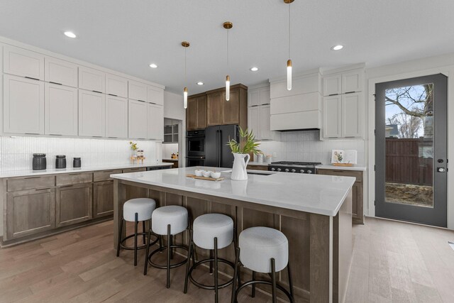 5012 Hankerson Ave, Edina, MN 55436 - kitchen with light wood-type flooring, decorative backsplash, freestanding refrigerator, a kitchen island, and a kitchen breakfast bar