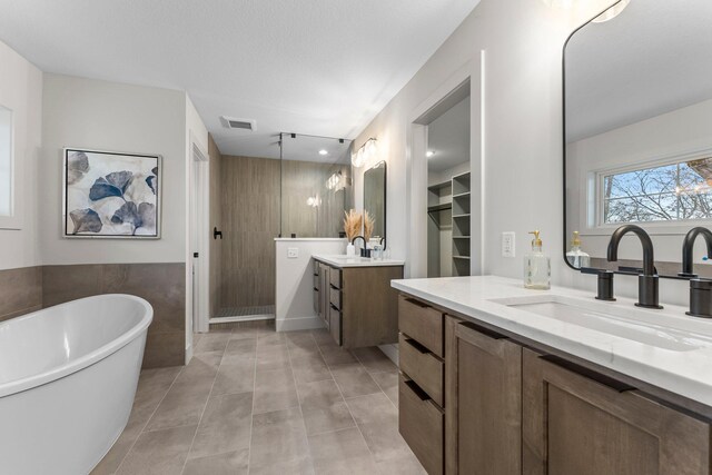 5012 Hankerson Ave, Edina, MN 55436 - full bathroom featuring a stall shower, two vanities, a freestanding tub, tile patterned floors, and tile walls