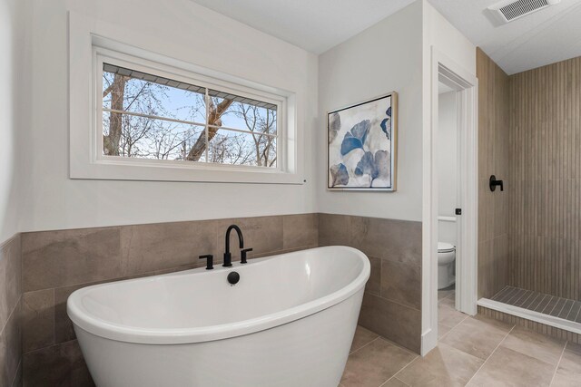 5012 Hankerson Ave, Edina, MN 55436 - bathroom with tile walls, a freestanding bath, a wainscoted wall, and tile patterned flooring