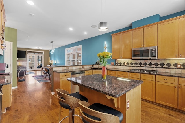 222 Ridgewood Ave, Minneapolis, MN 55403 - kitchen with appliances with stainless steel finishes, a peninsula, wood finished floors, recessed lighting, and tasteful backsplash