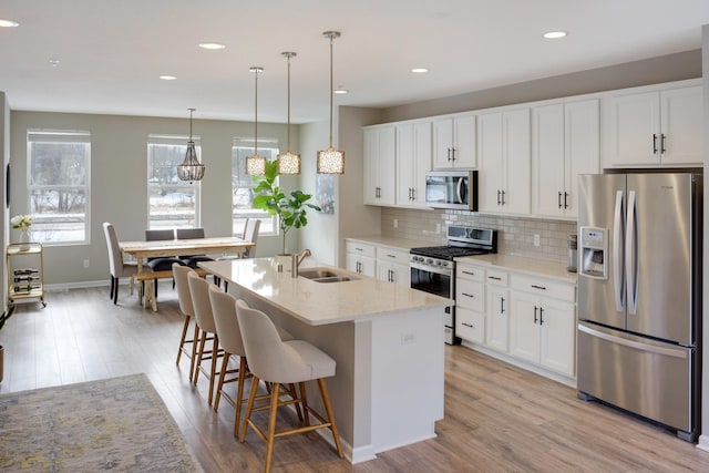 kitchen featuring a sink, backsplash, light wood-type flooring, and appliances with stainless steel finishes