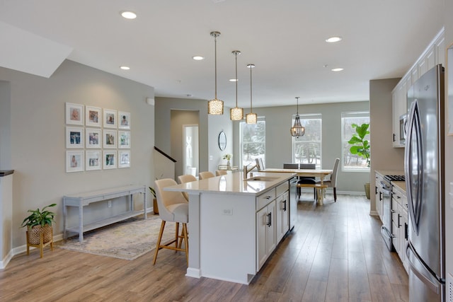 kitchen with stainless steel appliances, a breakfast bar, baseboards, and white cabinetry