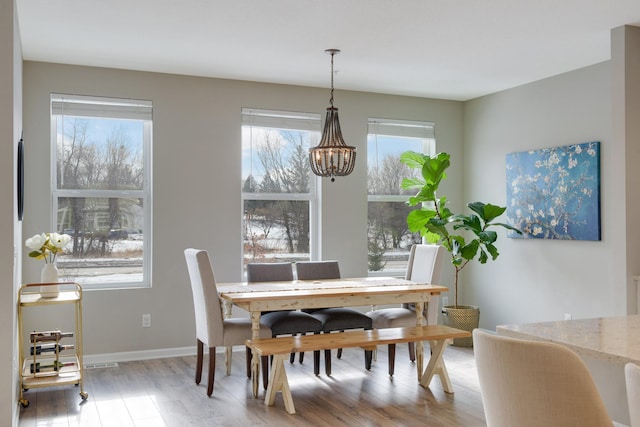 dining room with a wealth of natural light, baseboards, an inviting chandelier, and wood finished floors