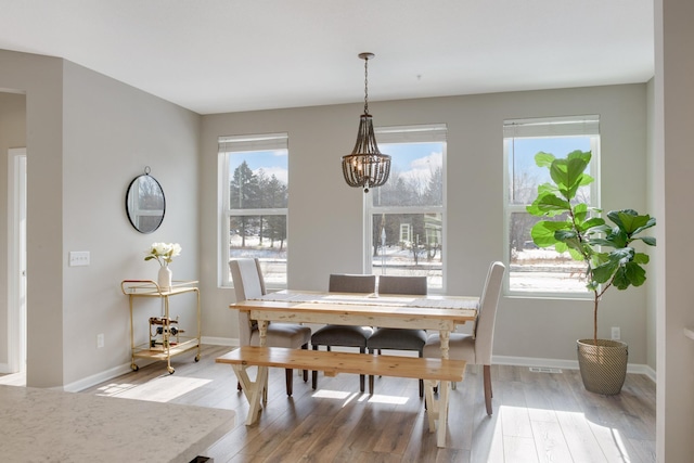 dining area with a chandelier, plenty of natural light, light wood finished floors, and baseboards