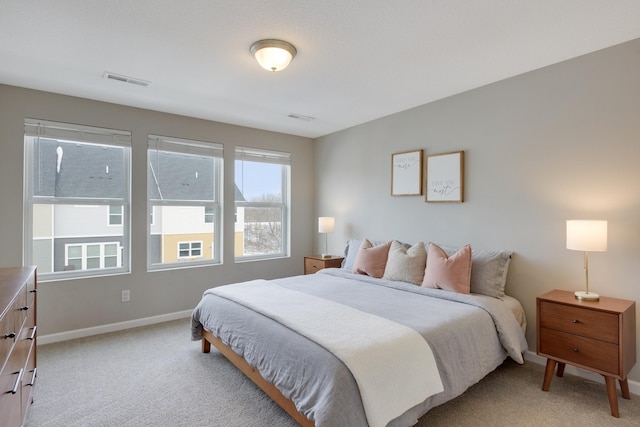 bedroom with visible vents, baseboards, and light carpet