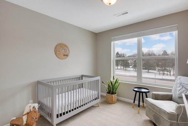 carpeted bedroom featuring baseboards, visible vents, and a nursery area