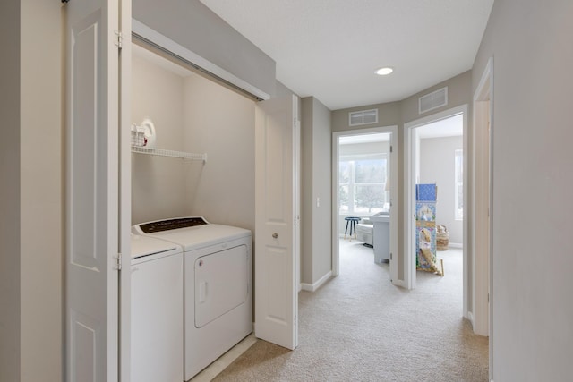 laundry area with independent washer and dryer, laundry area, light colored carpet, and visible vents