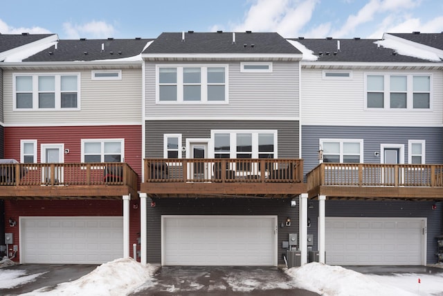 snow covered rear of property featuring driveway and an attached garage