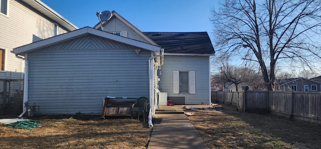 back of property with a fenced backyard and roof with shingles