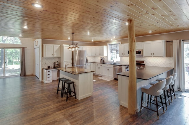 kitchen featuring stainless steel appliances, a breakfast bar, a sink, wood ceiling, and healthy amount of natural light