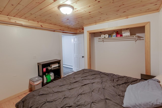 bedroom with wood ceiling, wood finished floors, baseboard heating, a closet, and baseboards