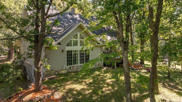 view of property exterior featuring a shingled roof and a lawn