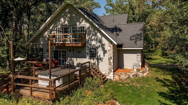 rear view of house with a lawn, a wooden deck, a balcony, and a shingled roof