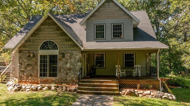 view of front facade with stone siding, a porch, and a shingled roof