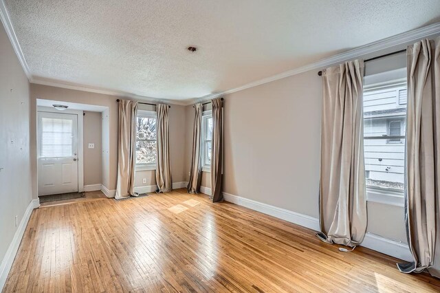 unfurnished room with light wood finished floors, baseboards, crown molding, and a textured ceiling
