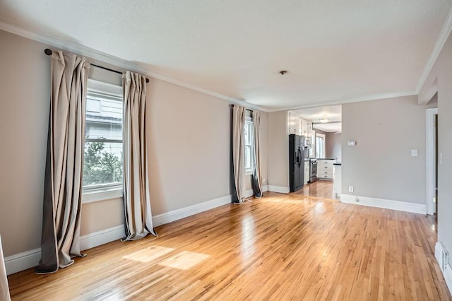 unfurnished living room featuring light wood finished floors, baseboards, and ornamental molding